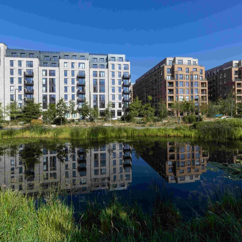 Photo of new apartments at Brent Cross Town, North London, with parkland and a lake in the foreground. (Brent Cross Town)