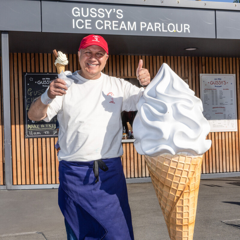 Photo of a smiling Gussy outside his ice cream parlour in Claremont Park, Brent Cross Town.