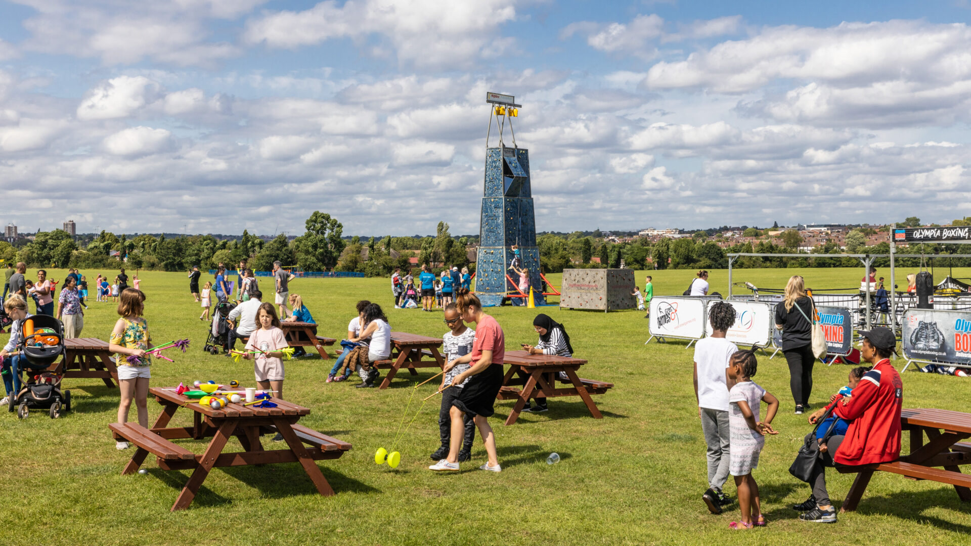 Gathering around picnic tables in park with climbing wall (Brent Cross Town)