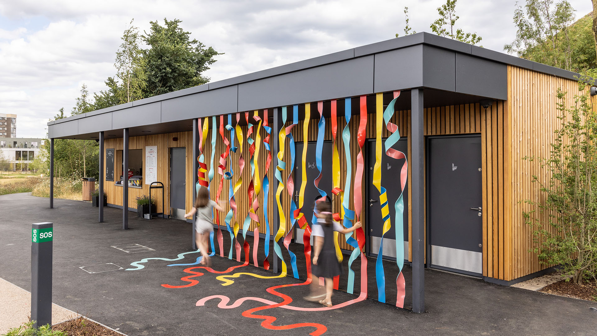 Photo of the colourful Rainbow of Ribbons installation by Hanna Benihoud at Claremont Park, Brent Cross Town. (Brent Cross Town)