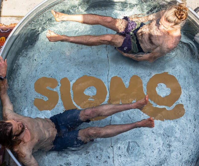 Photo of two people in a plunge pool with the word 'Slomo' painted on the bottom. (Brent Cross Town)