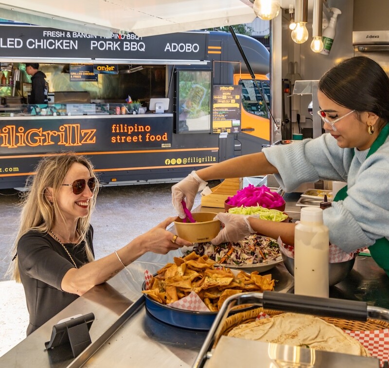 Photo od a person being served street food in the sunshine. (Brent Cross Town)