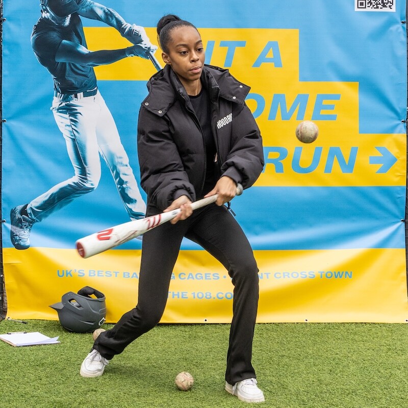 Photo of a woman hitting a ball with a baseball bat at The Play Offs. (Brent Cross Town)